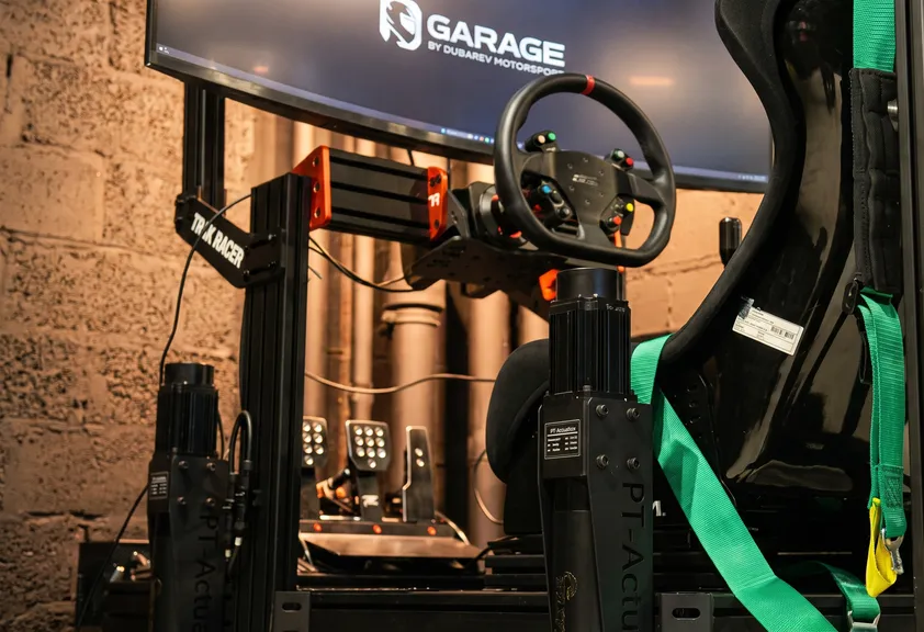 Статичный гоночный симулятор в клубе Garage: руль с прямым приводом, нагрузочные педали и гоночный ковш с ремнями