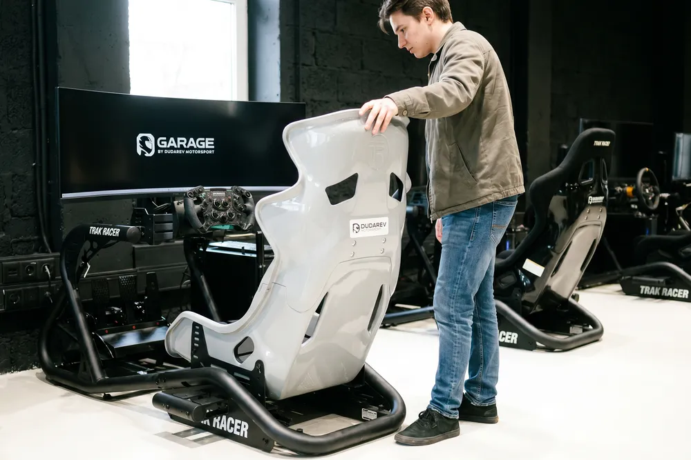 Сборка гоночного кокпита в клубе Garage: карбоновый ковш на раме TRAK RACER, прямоприводный руль, нагрузочные педали и изогнутый экран — единая техническая база всех форматов
