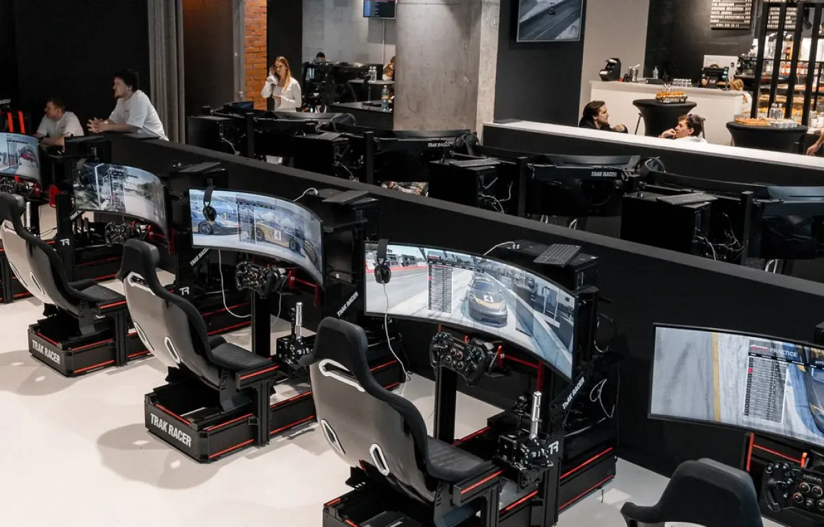 Зал клуба Garage в Москве: ряды гоночных кокпитов Trak Racer с изогнутыми экранами и кофейня на фоне